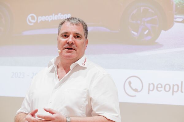 Männliche Person steht vor einer Leinwand und begrüßt die Gäste.