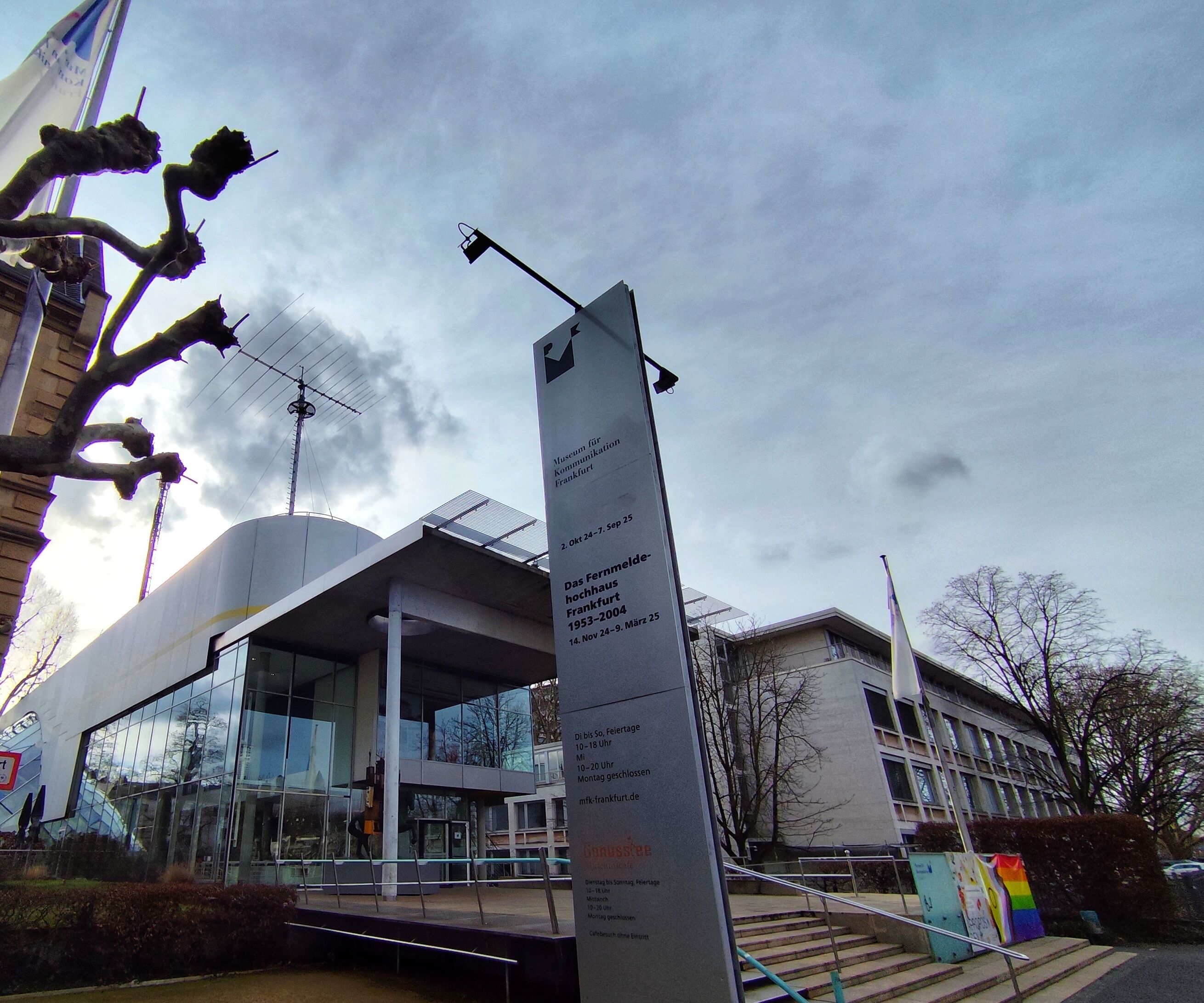 Verglaster Eingangsbereich Museum für Kommunikation mit Blick auf den Wolkenhimmel.