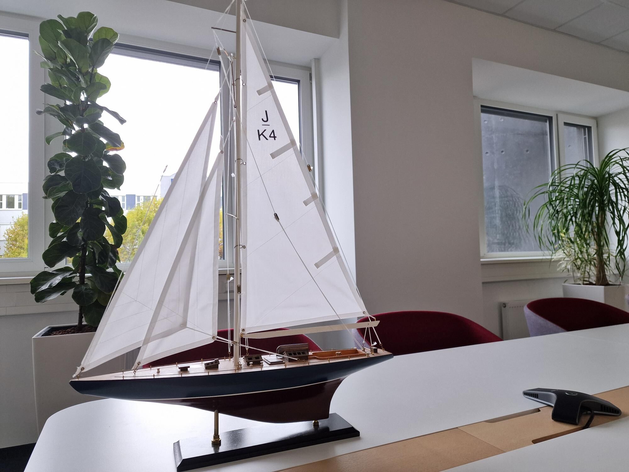 Segelschiff steht auf einem Bürotisch vor einem Fenster.