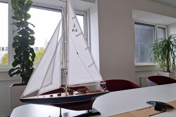 Ein Segelschiff steht auf dem Konferenztisch. Im Hintergrund sind Fenster.