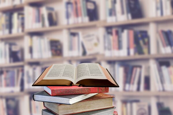 Aufgeschlagenes Buch vor einem Bücherregal.