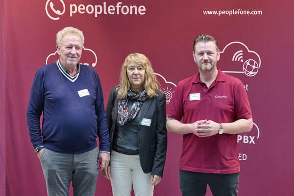 Partner der peoplefone stehen vor einer Fotowand