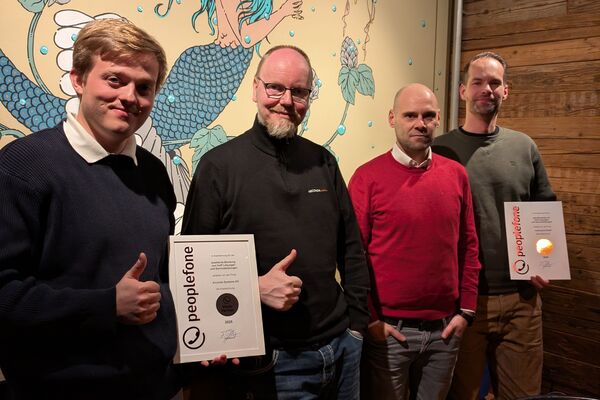 Vier Personen stehen vor einer farbigen Wand und zeigen ihre Urkunden.