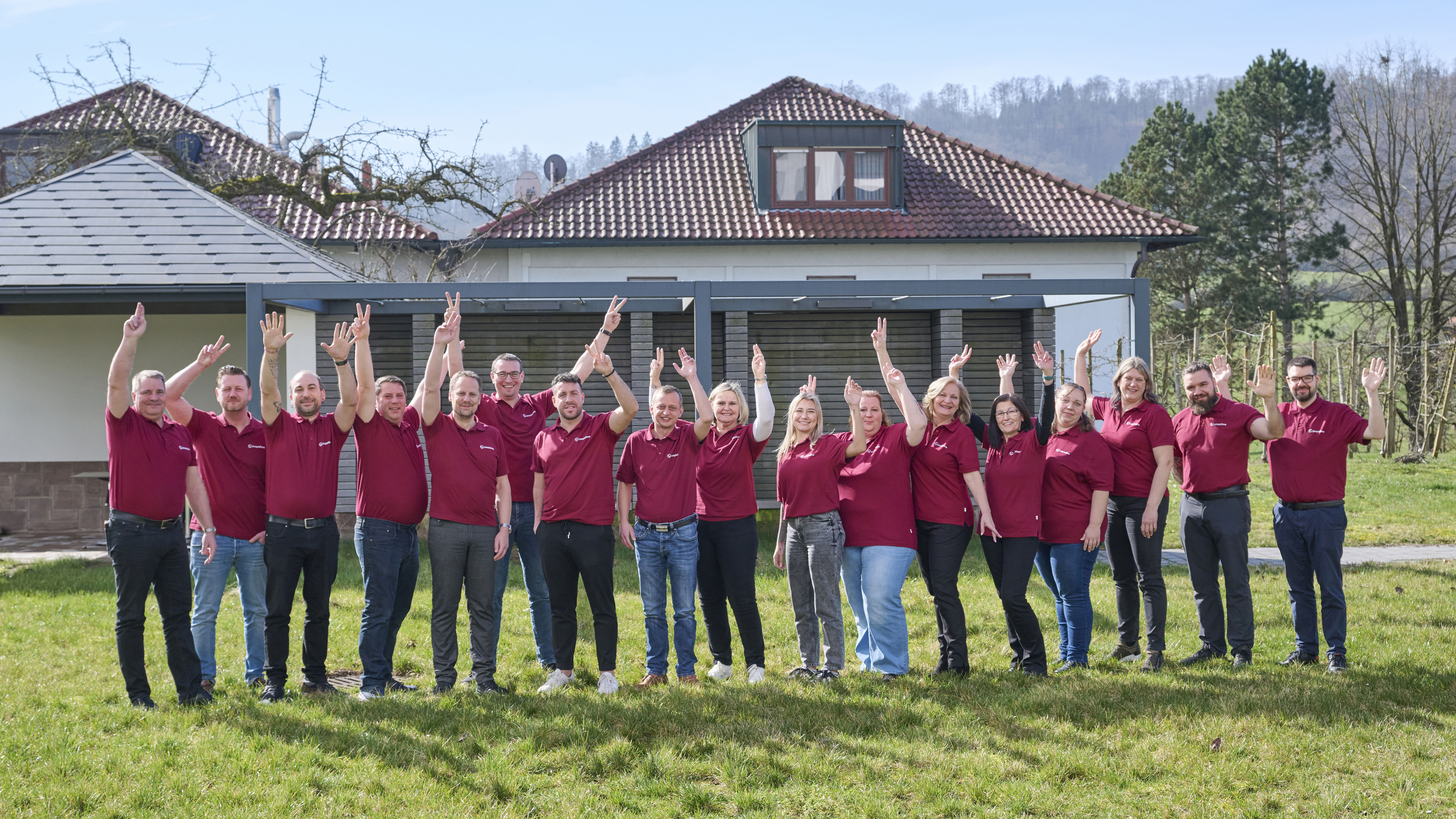 peoplefone Team winkend vor einem Gebäude.