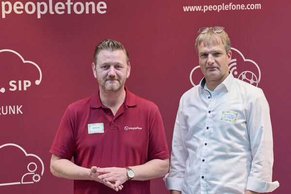 Partner der peoplefone stehen vor einer Fotowand