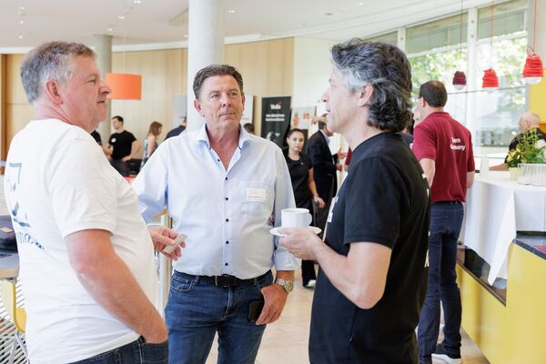 Bildausschnitt von Besuchern an einem Messestand im Gespräch.