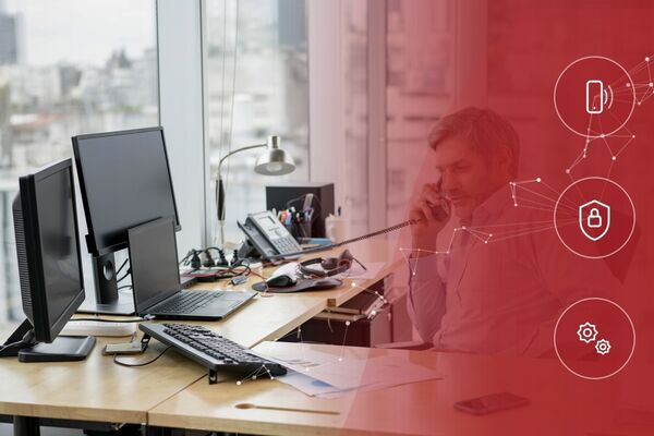 Männliche Person sitzt am Schreibtisch und telefoniert.
