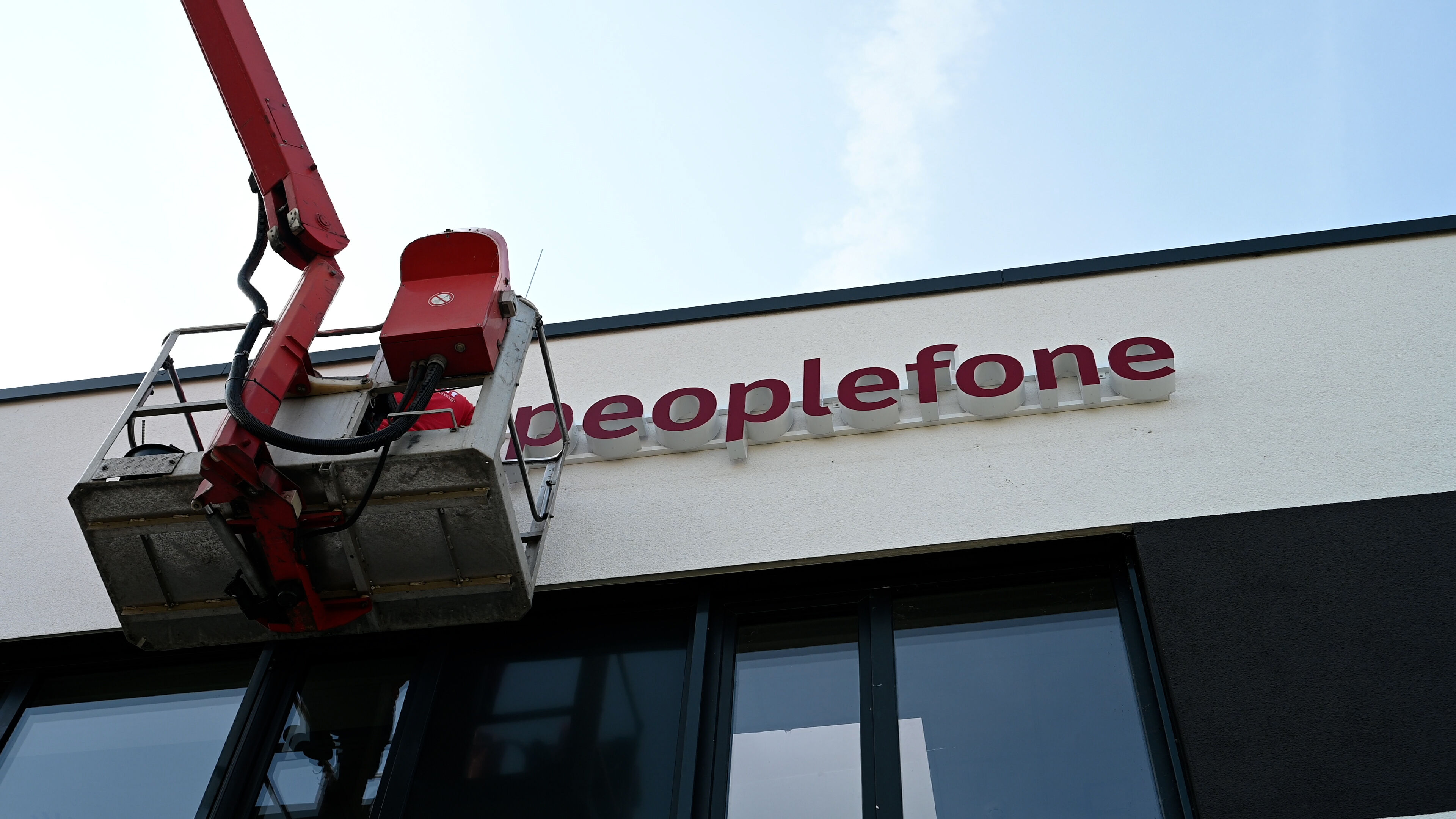 Eine Person installiert das peoplefone Logo an der Hauswand.