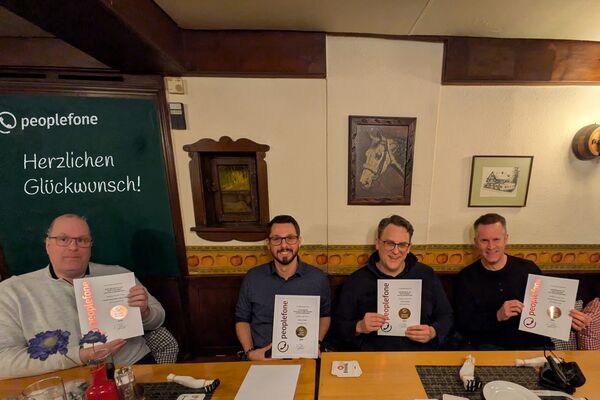 Vier Personen sitzen mit Urkunden in der Hand auf einer Holzbank.