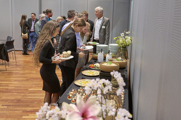 Personen stehen an einem Vorspeisenbuffet an.