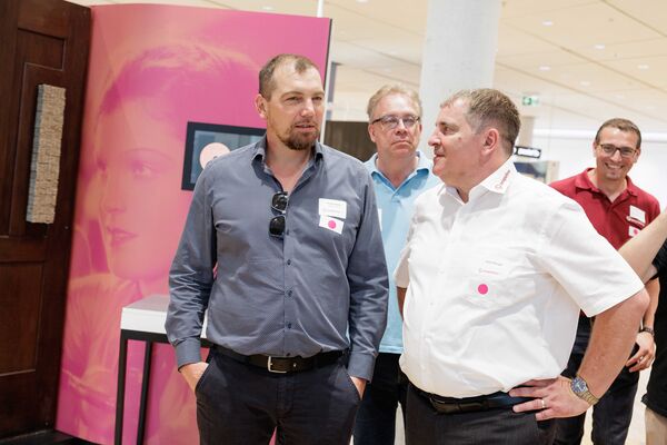 Mehrere Personen stehen in der Ausstellung und hören zu.