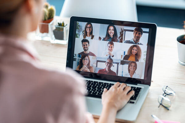 Weibliche Person sitzt vor einem Laptop und macht eine Videokonferenz.