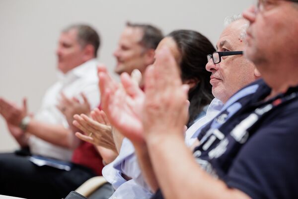Applaudierende Zuschauer in einer Stuhlreihe.