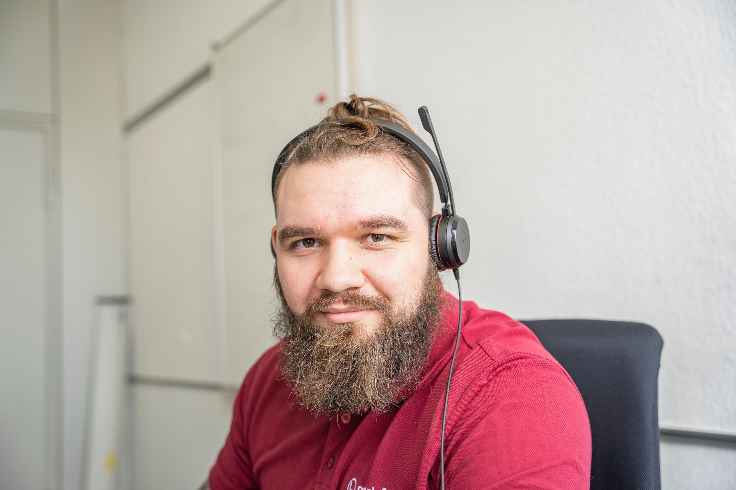 peoplefone Mitarbeiter sitzt am Schreibtisch und schaut in die Kamera.