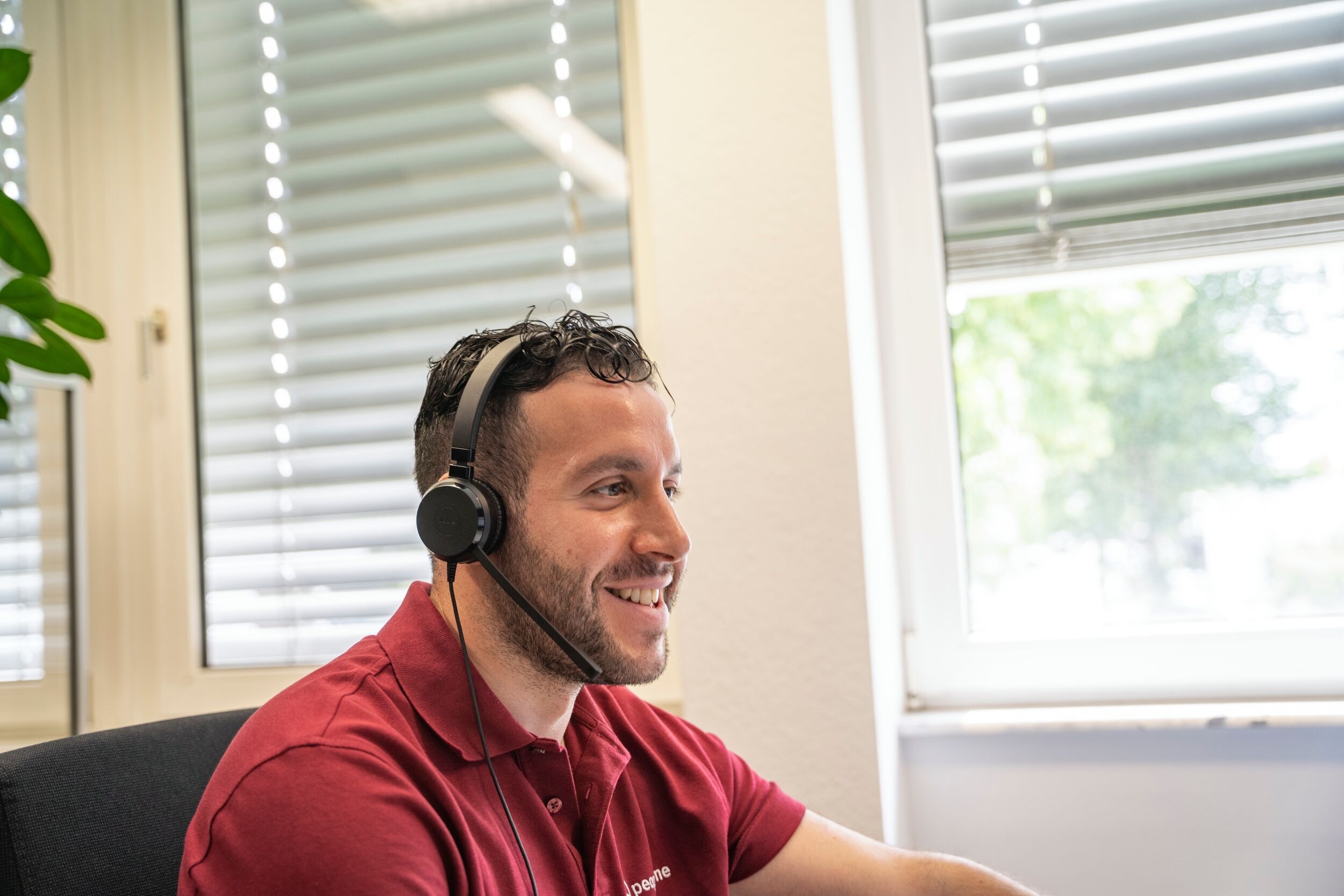 peoplefone Mitarbeiter telefoniert mit Headset im Büro.