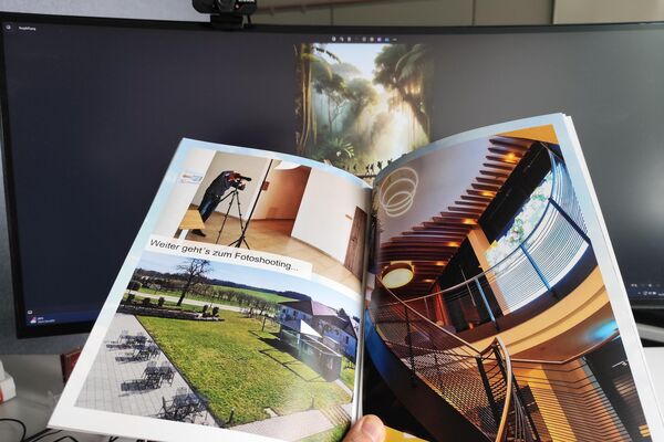 Aufgeschlagene Broschüre vor einem Bildschirm.