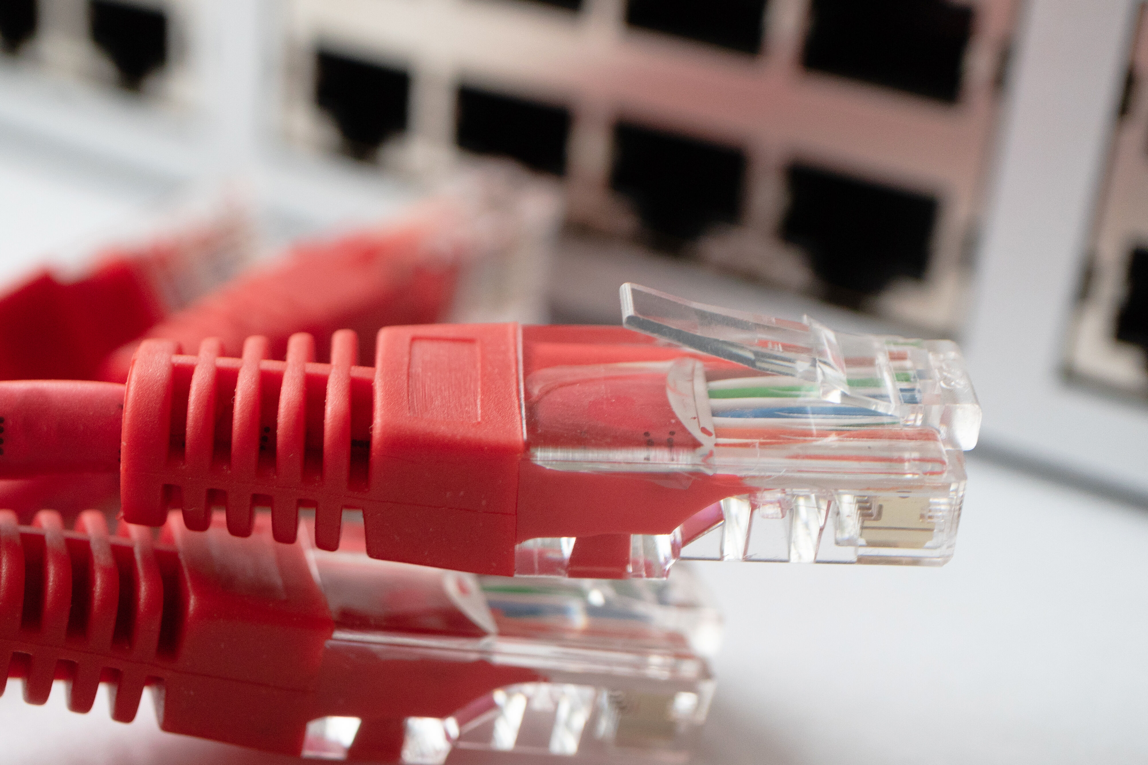 Vier rote LAN-Kabel liegen vor einer Router-Box.