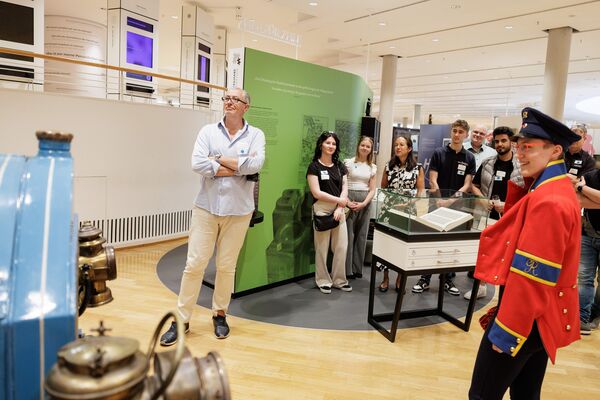 Mehrere Personen stehen in der Ausstellung und hören zu.