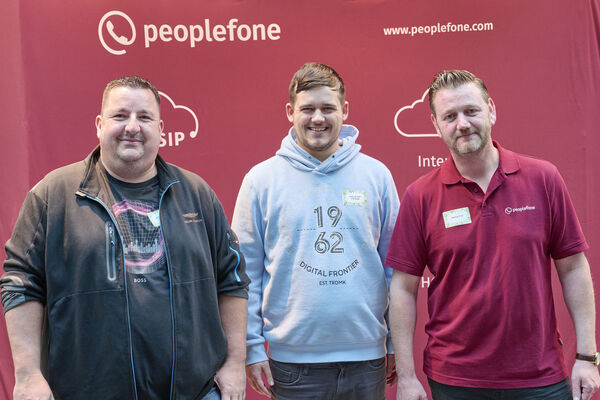 Partner der peoplefone stehen vor einer Fotowand