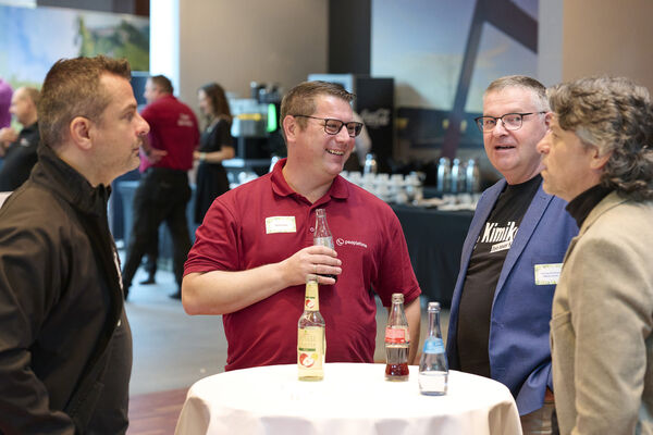 Personen stehen am Messestand und unterhalten sich.