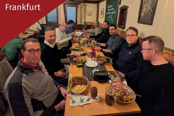 Mehrere Personen sitzen an einem langen Tisch und essen.