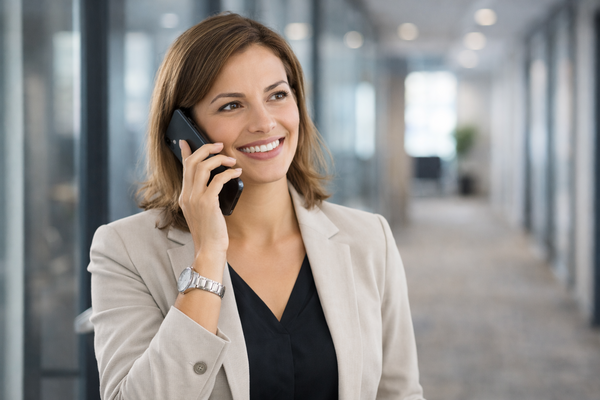 Weibliche Person steht im Flur eines Büros und telefoniert mit Handy.