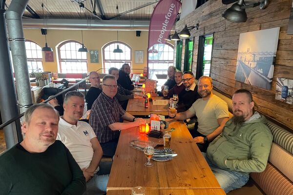 Mehrere Personen sitzen an einem Holztisch und unterhalten sich.