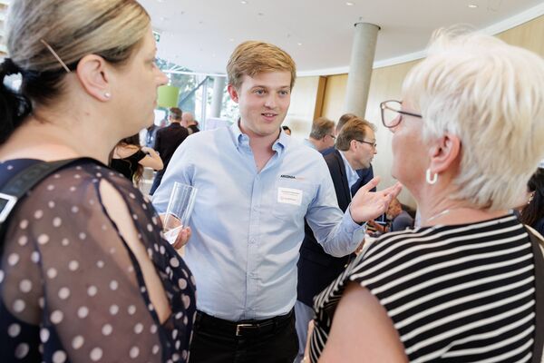 Drei Personen stehen im Kreis und unterhalten sich.