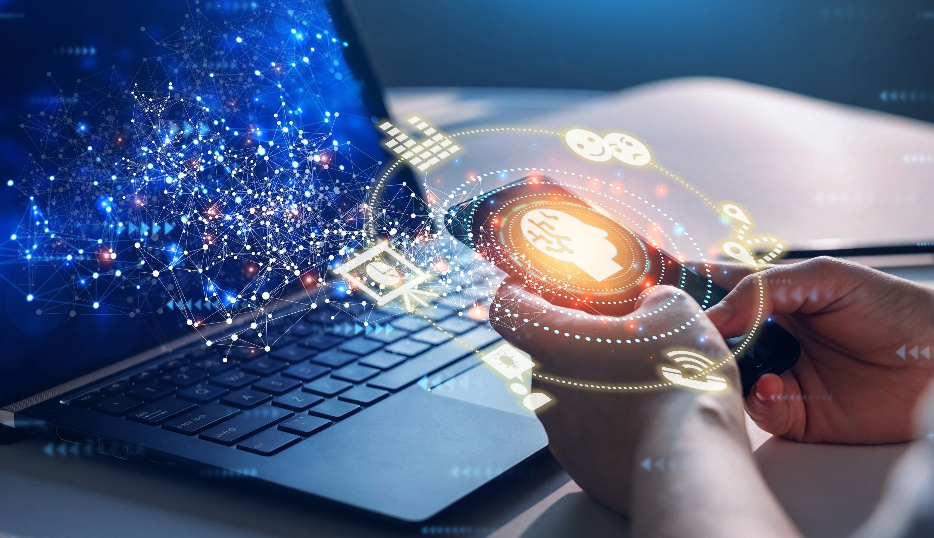 Zwei Hände halten ein Handy in Richtung eines Laptops. Es werden virtuell Daten übertragen und empfangen.