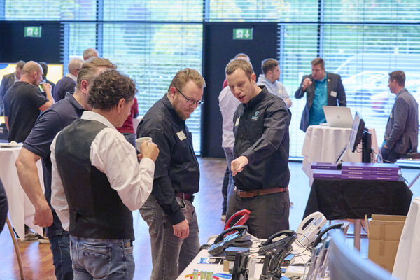 Personen stehen am Messestand und unterhalten sich.