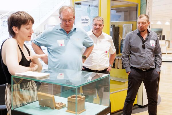 Mehrere Personen stehen in der Ausstellung und hören zu.