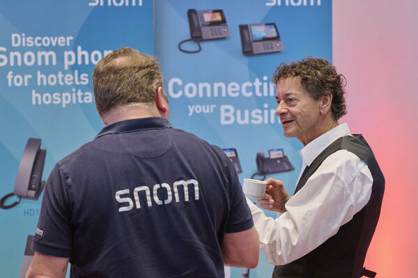 Personen stehen am Messestand und unterhalten sich.