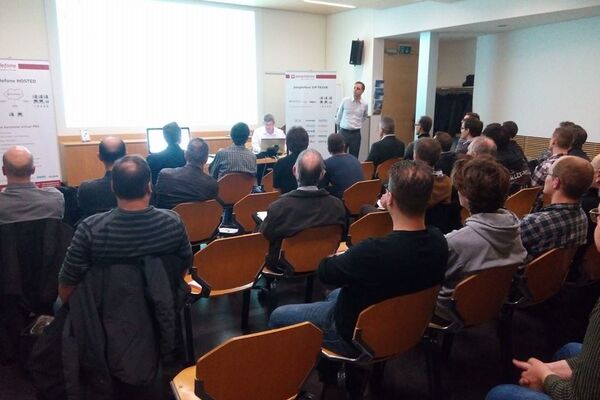 Stuhlreihen mit peoplefone Partnern, die auf eine Bildschirmleinwand schauen und dem Referenten zuhören.