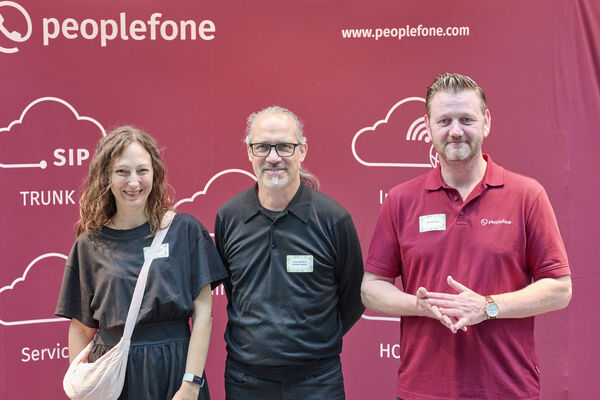 Partner der peoplefone stehen vor einer Fotowand