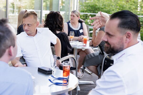 Mehrere Personen sitzen auf einer Terrasse und unterhalten sich.