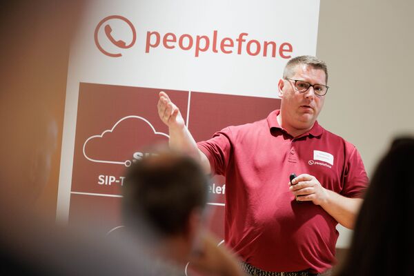 Eine Person steht vor einem Banner und hält einen Vortrag. Im Hintergrund ist eine Präsentation geöffnet.